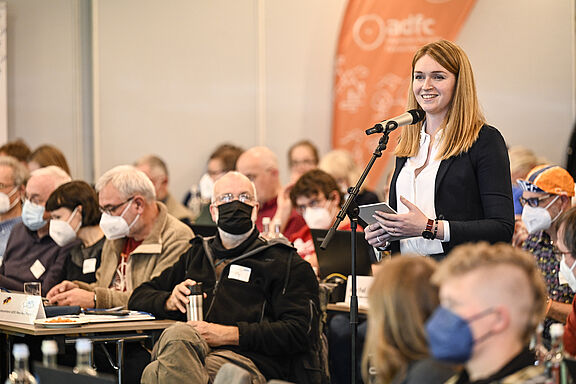 Rebecca Peters steht zwischen den sitzenden Delegierten