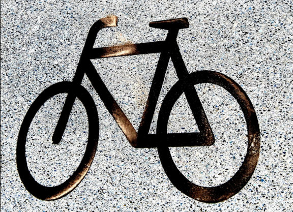 Ein schwarzes Fahrrad-Piktogramm auf Asphalt. 