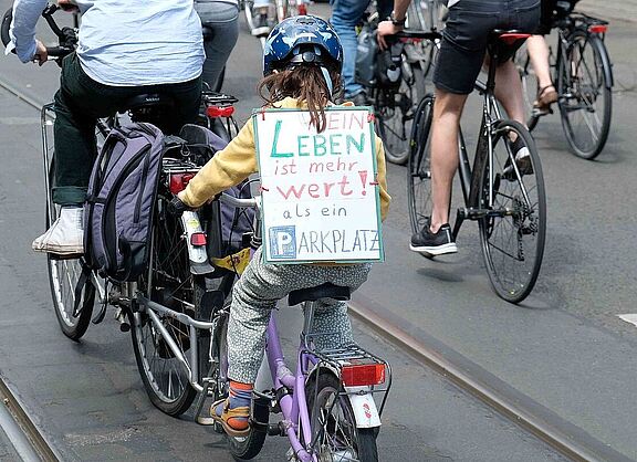 Ein kleines Mädchen auf dem Fahrrad von hinten mit einem Schild auf einer Demonstration gegen den Radwege-Stopp in Berlin.
