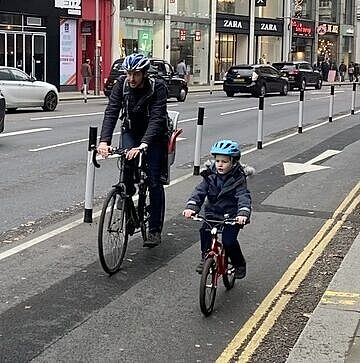 Mann und Kind fahren Rad auf einem geschützen Radweg in London