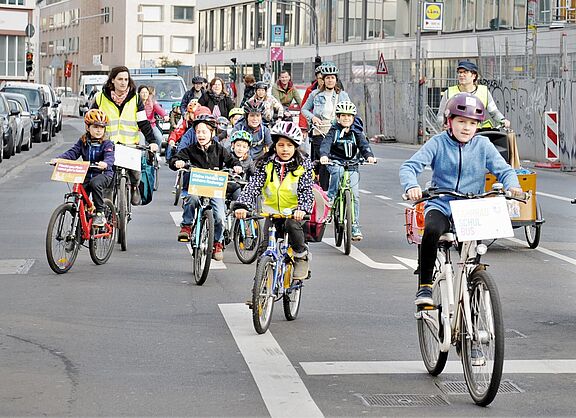Beim Fahrradbus fahren Kinder und Eltern in der Gruppe auf der Straße.