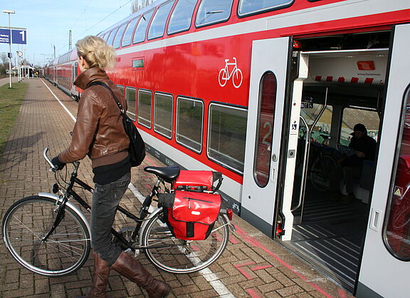 Frau mit Rad steigt aus Regionalzug