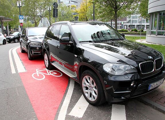 Schwarzer SUV parkt auf rot markiertem Radfahrstreifen