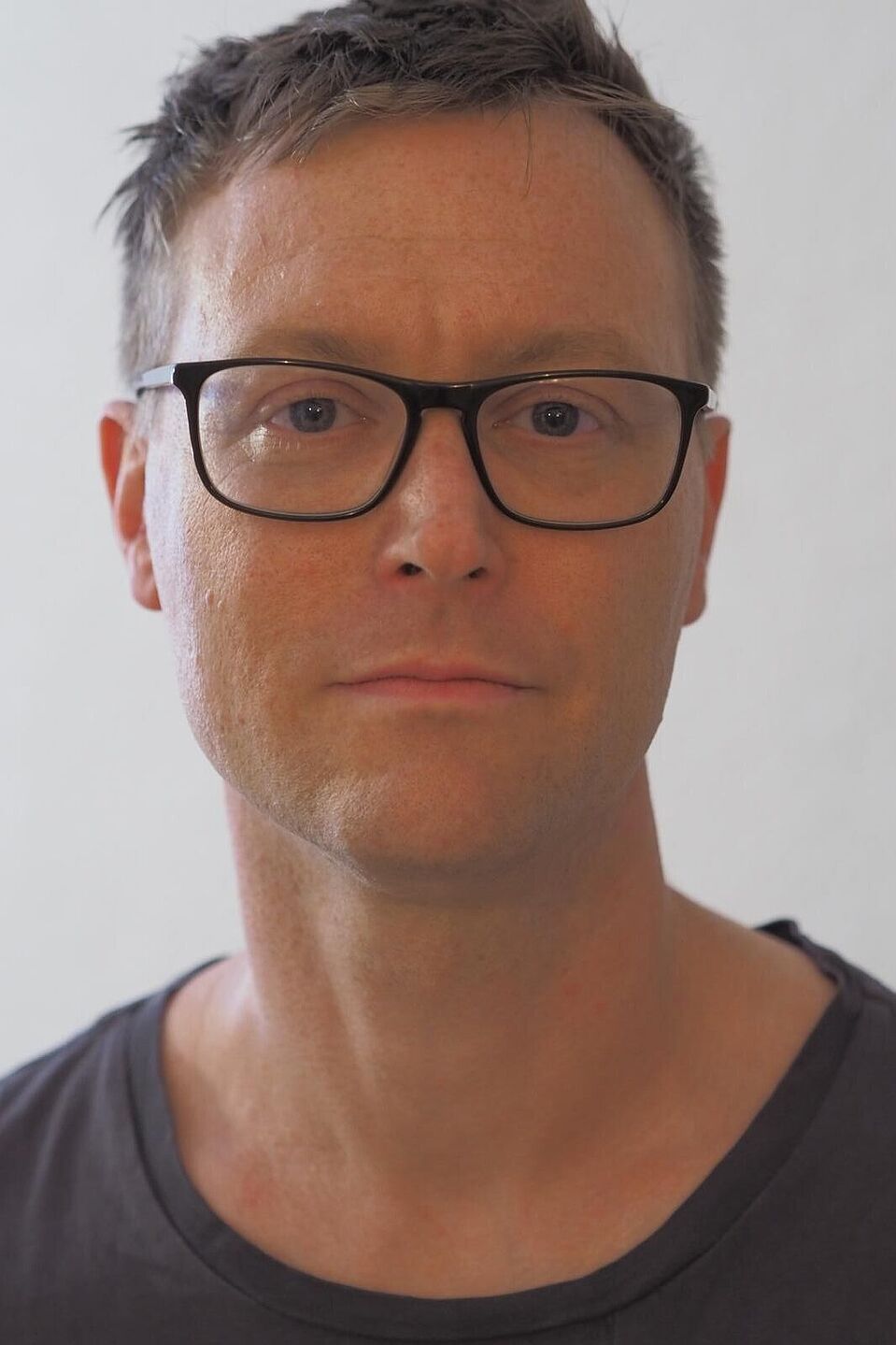 Dr. Rul von Stülpnagel Porträtfoto von Dr. Rul von Stülpnagel: Mann mit kurzen braunen Haaren, schwarzer Brille und grauem T-Shirt vor weißem Hintergrund.