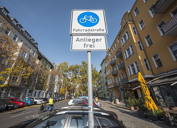 Blick auf ein Verkehrszeichen "Fahrradstraße" am Eingang einer Straße mit Wohnhäusern auf beiden Seiten. 